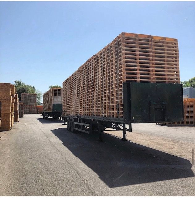 Trailer loaded with tall stacks of wooden pallets