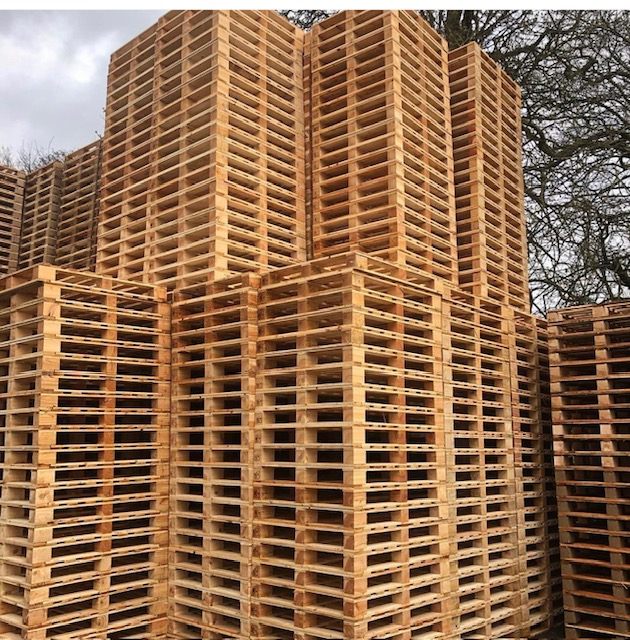 Tall stacks of wooden pallets stored outdoors
