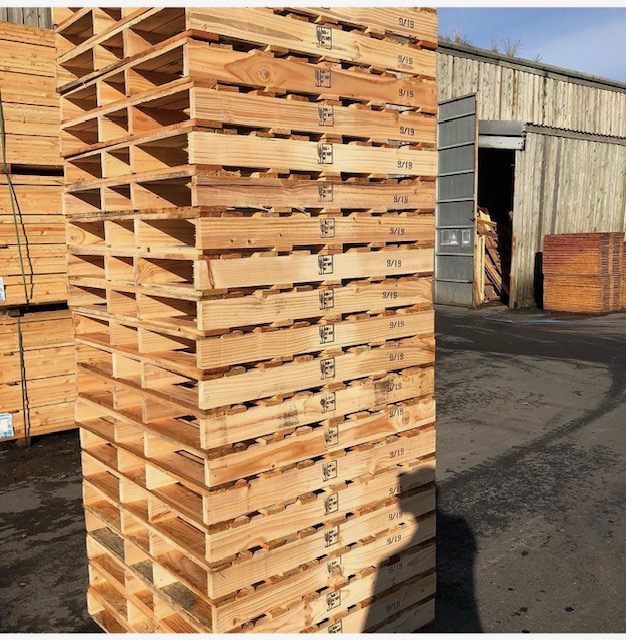 Tall stack of timber pallets with treatment marks